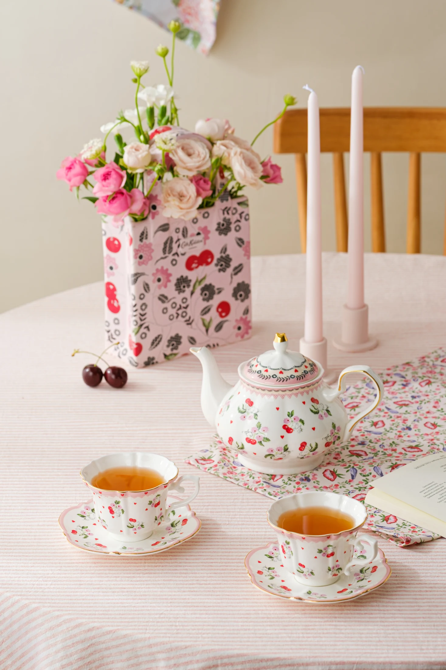 Cath Kidston cherry-patterned teapot and cups beside flowers